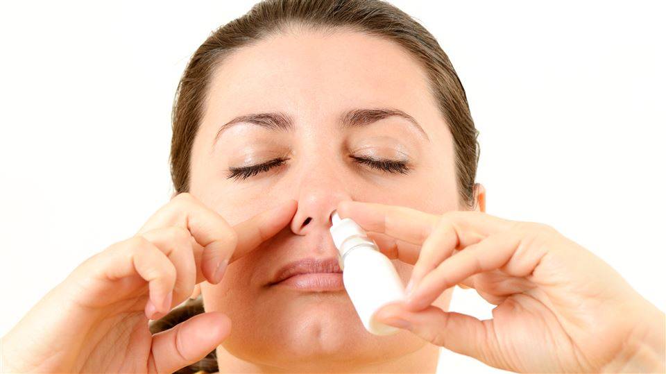 Image of a woman using nasal spray